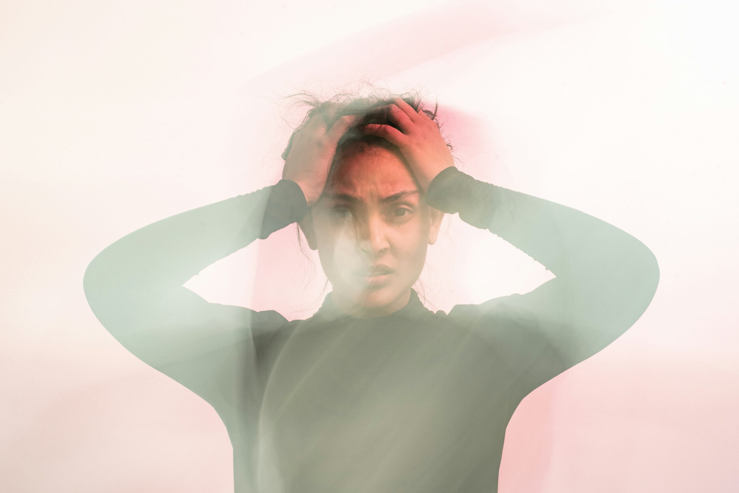 Woman gripping her head with both hands in a motion-blurred photo, showing nervous system dysregulation